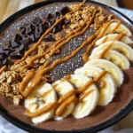 - 2 frozen bananas - 1 cup almond milk (or milk of choice) - 2 tablespoons unsweetened cocoa powder - 2 tablespoons natural peanut butter - 1 tablespoon honey or maple syrup (optional) - 1 teaspoon vanilla extract The main ingredients create a thick and creamy base for the smoothie bowl. The frozen bananas give it a nice chill and smoothness. Almond milk adds creaminess without being too heavy. Unsweetened cocoa powder gives the rich chocolate flavor. Natural peanut butter adds a nutty taste and protein. Honey or maple syrup adds sweetness, but it's optional. The vanilla extract brings all the flavors together. - Sliced bananas - Granola - Dark chocolate shavings - Chia seeds - Drizzle of peanut butter Toppings make your smoothie bowl fun and tasty. Sliced bananas add freshness and texture. Granola gives a crunchy bite. Dark chocolate shavings add a sweet touch of chocolate. Chia seeds are tiny but packed with nutrients. A drizzle of peanut butter on top adds extra flavor and richness. You can mix and match toppings based on what you like! - Step 1: Combine the frozen bananas, almond milk, cocoa powder, peanut butter, honey, and vanilla extract in a blender. - Step 2: Blend on high until smooth and creamy. Stop to scrape down the sides if needed. - Step 3: Pour the smoothie mixture into a bowl. - Step 4: Arrange your sliced bananas and granola on top of the smoothie base. - Step 5: Top with chia seeds, dark chocolate shavings, and a drizzle of peanut butter. - Step 6: Serve immediately for the best taste and texture. Follow these simple steps, and you'll create a delicious chocolate peanut butter smoothie bowl in no time! - Use frozen bananas for a creamier texture. They make your smoothie thick and rich. - Adjust almond milk to get your desired consistency. Add more for a thinner bowl. - Scrape down the sides of the blender for even blending. This helps to mix all ingredients well. - If you want extra sweetness, try adding honey or maple syrup. Start with one tablespoon. - You can also use alternate sweeteners for different diets. Stevia or agave work well too. {{image_2}} You can change up the taste of your smoothie bowl in simple ways. - Add spinach or kale: This gives a boost of greens without changing the flavor much. - Experiment with different nut butters: Almond or cashew butter can add new taste profiles. - Include protein powder: This adds more nutrition and makes it a filling meal. You can easily make this bowl fit your diet. - Dairy-free options: Use almond or coconut milk for a creamy base without dairy. - Gluten-free alternatives for toppings: Choose gluten-free granola to keep it safe for all diets. - Adjusting for vegan diets: Swap honey for maple syrup to keep it vegan-friendly. To store any leftover smoothie, place it in an airtight container. Keep it in the fridge for up to 24 hours. If you want to save it longer, consider freezing it. Pour the smoothie into ice cube trays for easy storage. Once frozen, pop the cubes into a bag. This way, you can enjoy smoothie cubes later. Can you re-blend the smoothie? Yes, you can! When you are ready to enjoy it again, just blend it again. Add a splash of milk to help with blending. This keeps the texture smooth and creamy. Avoid microwaving as it can change the texture and flavor. Re-blending is the best way to keep it delicious! To make this yummy smoothie bowl, follow these steps: 1. Combine Ingredients: In a blender, mix frozen bananas, almond milk, cocoa powder, peanut butter, honey (if you want it sweeter), and vanilla extract. 2. Blend: Blend the mix on high speed until it's smooth and creamy. Stop to scrape down the sides if needed. 3. Serve: Pour your thick smoothie into a bowl. 4. Add Toppings: Top it with sliced bananas, granola, chia seeds, dark chocolate shavings, and a drizzle of peanut butter. Enjoy it right away! Yes, you can use fresh bananas, but it will change the texture. Fresh bananas make the smoothie thinner and less creamy. If you want a thicker bowl, freeze your bananas before blending. This smoothie bowl packs many nutrients. Here are some benefits: - Bananas provide potassium and fiber. - Cocoa powder is rich in antioxidants. - Peanut butter adds healthy fats and protein. - Almond milk is lower in calories than regular milk. - Chia seeds offer omega-3 fatty acids and more fiber. You can get creative with toppings! Here are some ideas: - Use berries like strawberries or blueberries for a fruity touch. - Add nuts like almonds or walnuts for crunch. - Include seeds like pumpkin or sunflower seeds for extra nutrition. - Drizzle honey or maple syrup for added sweetness. - Experiment with coconut flakes or yogurt for a different flavor. Yes, you can prep this smoothie bowl ahead of time. Here's how: - Smoothie Base: Make the smoothie mix and store it in an airtight container in your fridge for up to 24 hours. - Toppings: Keep toppings separate until you are ready to eat. Adding them right before serving keeps them fresh. - Freezing: You can also freeze the smoothie base. Just blend it and pour it into a container. When you want to eat it, let it thaw before adding your toppings. This blog post shows how to make a tasty chocolate peanut butter smoothie bowl. We covered the main ingredients, step-by-step instructions, and helpful tips. Remember, using frozen bananas makes your smoothie creamy. You can also mix in different flavors or adjust toppings for your taste. Lastly, store leftovers properly to keep them fresh. Enjoy making this delicious treat that is both fun and healthy!