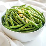 You need 1 pound of fresh green beans for this recipe. Make sure to trim the ends. Fresh beans give the best taste and crunch. You can find them in the produce section of your grocery store. Look for bright green, firm beans with no blemishes. Next, grab 3 tablespoons of olive oil. This oil adds flavor and helps the beans crisp up. You can use other oils like avocado oil if you prefer. Just remember, oil is key for that tasty texture. For flavor, you will need: - 3 cloves garlic, minced - 1/2 cup grated Parmesan cheese - 1 teaspoon Italian seasoning - 1/2 teaspoon red pepper flakes (optional) - Salt and pepper to taste The garlic gives a nice aroma, and Parmesan adds a salty, cheesy kick. Italian seasoning blends herbs like basil and oregano for extra depth. If you like heat, toss in red pepper flakes. Adjust salt and pepper to fit your taste. These simple ingredients make this dish so delicious! Preheating your air fryer is key to getting great results. Set your air fryer to 400°F (200°C) and let it heat for about 5 minutes. This step helps to cook the green beans evenly and gives them that nice crisp. Start by trimming 1 pound of fresh green beans. Use a large bowl to mix the green beans with 3 tablespoons of olive oil, 3 cloves of minced garlic, and 1 teaspoon of Italian seasoning. If you like some heat, add 1/2 teaspoon of red pepper flakes. Season with salt and pepper to taste. Toss everything well so the green beans are fully coated. Next, add 1/2 cup of grated Parmesan cheese to the mix. Combine it all again. This cheese adds a rich flavor that pairs perfectly with the garlic. Once your green beans are coated, place them in the air fryer basket. Make sure to arrange them in a single layer. If your basket is small, you might need to cook in batches. Air fry the green beans for 8 to 10 minutes. Halfway through, shake the basket to help them cook evenly. They should come out tender and slightly crispy. After cooking, sprinkle the remaining Parmesan cheese on top. Return the basket to the air fryer for 2 more minutes. This melts the cheese and makes it extra tasty. Finally, carefully remove the green beans from the air fryer and serve them hot. Enjoy this delicious and easy side dish! To get that perfect crispiness, preheat your air fryer to 400°F. This step is key. It helps the green beans cook evenly. Cook for about 8-10 minutes. Shake the basket halfway through. This ensures every bean gets that nice crunch. If you want them crispier, add an extra minute. Just keep an eye on them so they don’t burn. Taste is very personal. You might like your green beans spicy or mild. Start with the basic salt and pepper. If you want more flavor, add extra garlic or Italian seasoning. The red pepper flakes add heat. Feel free to skip them if you prefer a milder taste. Always taste your mixture before cooking. It’s easier to adjust before it’s in the air fryer. Olive oil is great, but it’s not your only option. You can use avocado oil for a different flavor. It can handle high heat well. If you're looking for a lighter option, try using a cooking spray. This helps cut down on calories while still giving a great texture. Just remember, the oil helps the cheese stick to the beans, so a little is key. {{image_2}} You can mix in other veggies for fun flavors. Try adding bell peppers, carrots, or zucchini. Cut them to match the green beans. This way, they all cook evenly. The air fryer will make them crispy and tasty. Parmesan is great, but you can swap it out. Try using Pecorino Romano for a sharper taste. Feta cheese adds a nice tang. Mozzarella gives a creamy texture. Mix and match to find your favorite! Spice things up by adding more heat. Try cayenne pepper or chili powder for a kick. If you like it mild, skip the red pepper flakes. You can also add lemon zest for a fresh taste. Experiment to see what you enjoy! After cooking your air fryer garlic Parmesan green beans, let them cool first. Place them in an airtight container. You can store them in the fridge for up to three days. Make sure to keep them away from strong-smelling foods. This helps maintain their flavor. To reheat, use your air fryer for the best results. Preheat it to 350°F (175°C). Place the green beans in the basket. Heat them for about 3-5 minutes. This will help keep them crispy. You can also use a microwave. Just heat for 30 seconds at a time, checking often. If you want to freeze your garlic Parmesan green beans, do so before cooking. After mixing them with oil and seasonings, spread them on a baking sheet. Place them in the freezer for about an hour. Once frozen, transfer them to a freezer bag. They can last up to three months. When you're ready to cook, no need to thaw. Just air fry them for a few extra minutes. Yes, you can use frozen green beans. Just remember to thaw them first. This helps them cook evenly. You may need to adjust the cooking time slightly. Start with 10 minutes and check for doneness. Frozen beans might take a bit longer to crisp up, but they will still taste great. To make this dish dairy-free, skip the Parmesan cheese. You can try dairy-free cheese or nutritional yeast instead. Both options add flavor without the dairy. Use about 1/2 cup of your choice. This keeps the green beans tasty while fitting your dietary needs. These garlic Parmesan green beans pair well with many main dishes. Try them with grilled chicken or fish for a light meal. They also go great with steak or pork chops. Serve them alongside pasta for a filling dinner. Whatever you choose, they add a delicious crunch! This blog post showed you how to make air-fried green beans. We covered key ingredients, like fresh green beans and olive oil. You learned step-by-step cooking instructions for perfect crispy results. I shared tips on seasoning and oil options. We also explored fun variations with other veggies and cheeses. Lastly, I provided storage info to keep your beans fresh. Enjoy your cooking adventure! You can make this dish your own.
